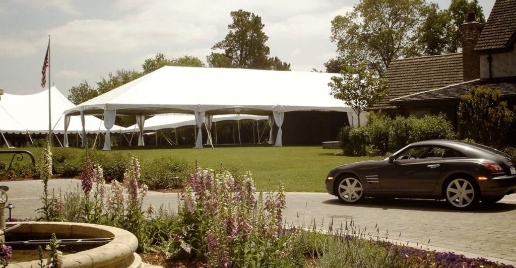 An image of a car parked outside some large tents