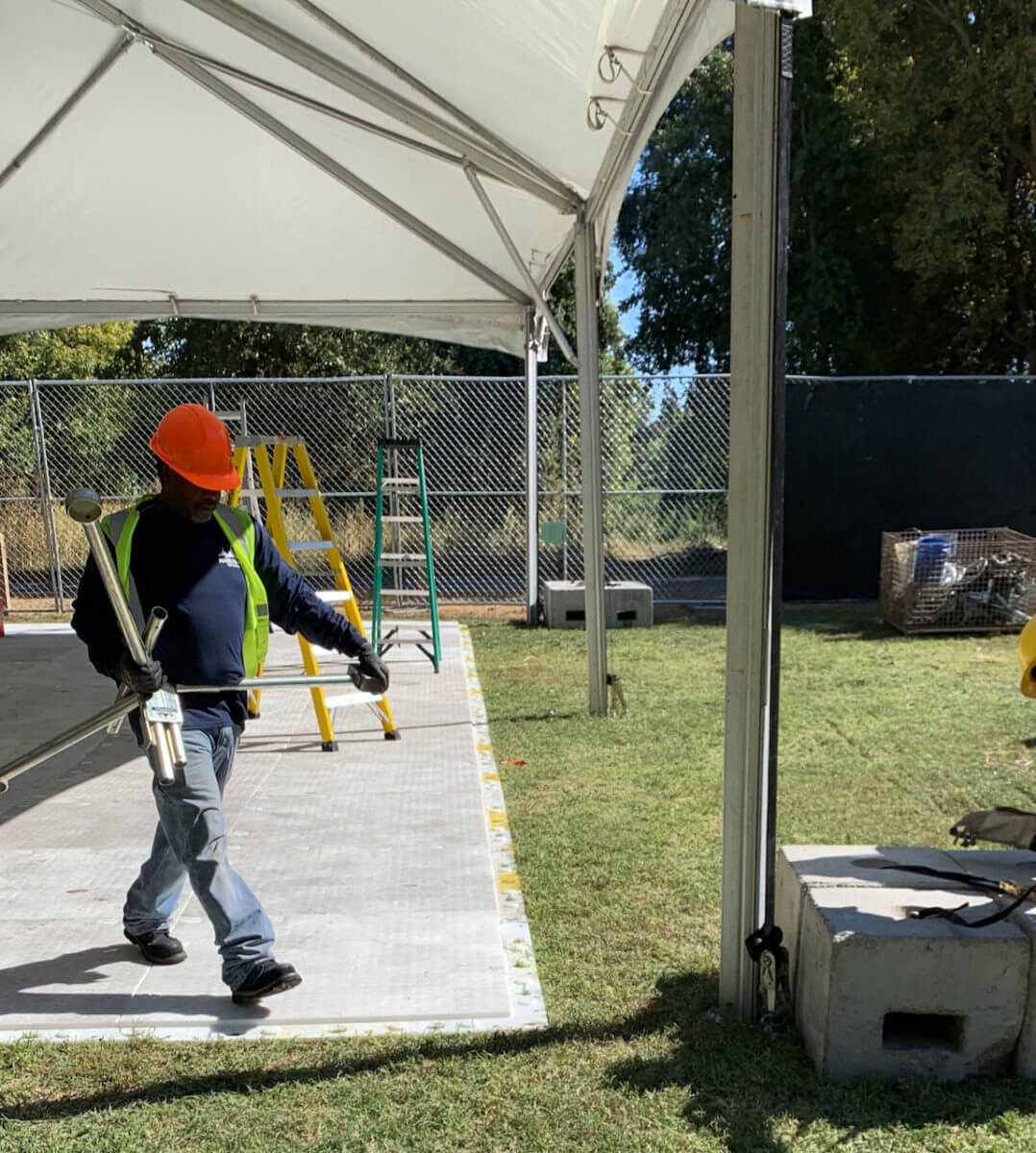 Image is a visual depiction of a crew member walking on the event subfloor offered as a rental item from Made in the Shade