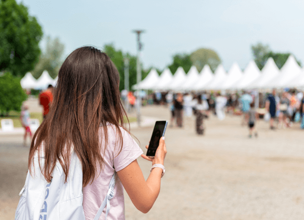 A woman uses a mobile app at a multi-day music festival.